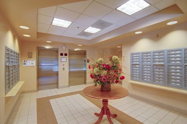 Lobby area featuring elevators and mailboxes with floral arrangement