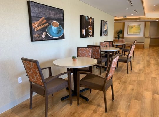Cozy common area with tables and chairs, featuring artwork on the walls.