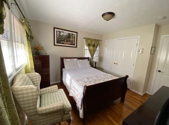 Well-furnished bedroom with a bed, armchair, and closet