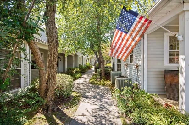 Pathway lined with trees and an American flag at Southside Gardens.