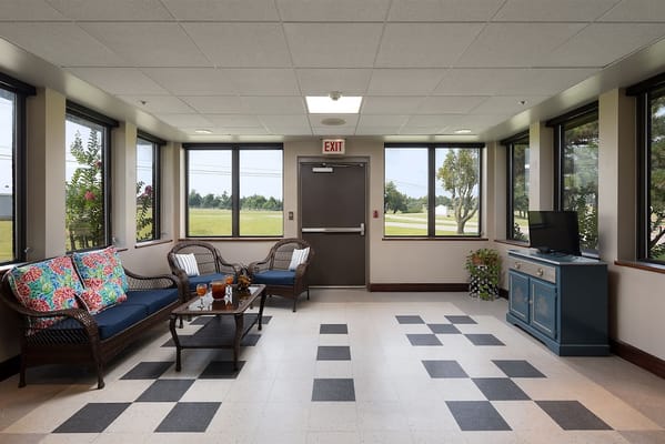 Lounge with seating and large windows in St. Ann's Skilled Nursing & Therapy