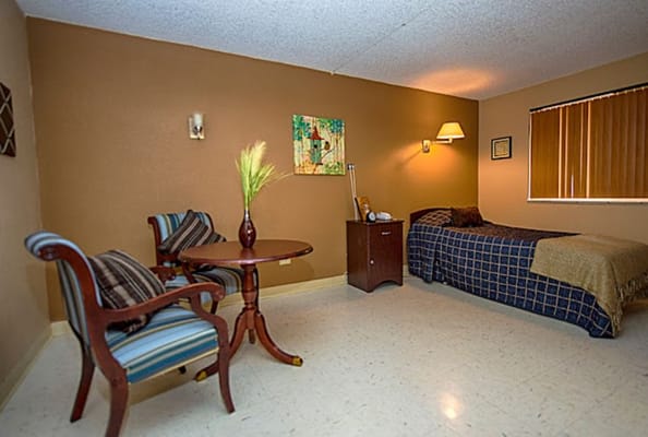 A cozy room with a bed, seating area, and artwork on the wall