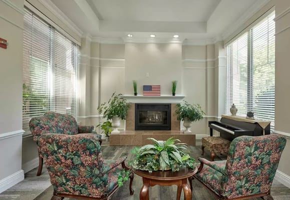 Lounge with seating, fireplace, and plants in a senior living facility