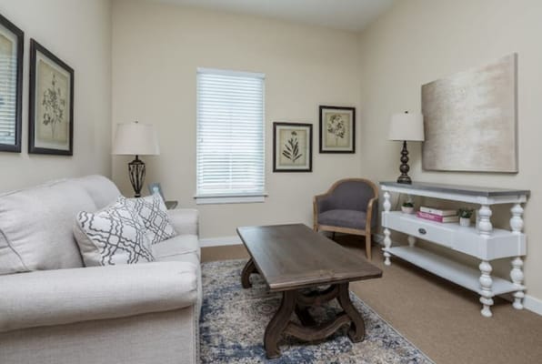 A cozy living room featuring a sofa, a coffee table, and decorative art on the walls.