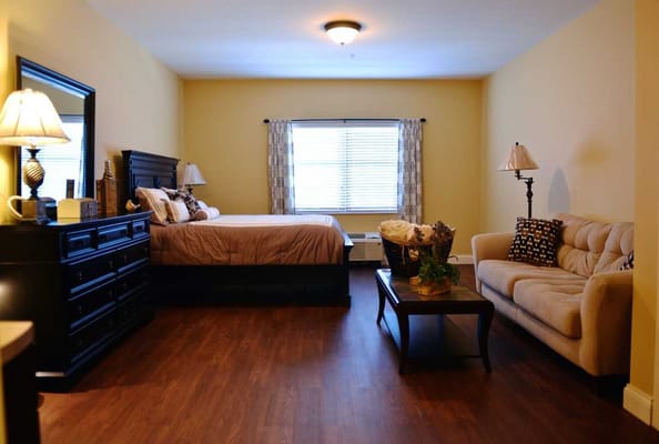 A well-furnished bedroom with a bed, dresser, and seating area.