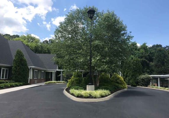Landscaped entrance with a tree and light pole