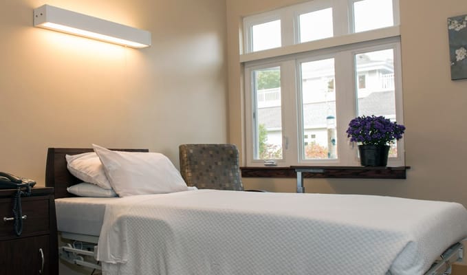 Bright interior of a resident's room with bed and chair