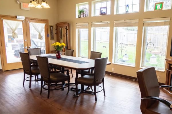 Bright dining area with a table and chairs, featuring large windows.