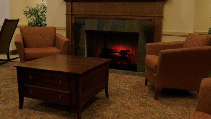 Lounge with two chairs, a coffee table, and a glowing fireplace