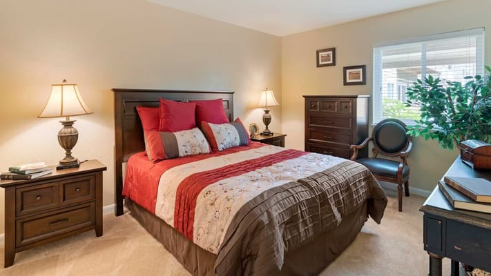A well-furnished bedroom with a bed, nightstand, and decorative elements.