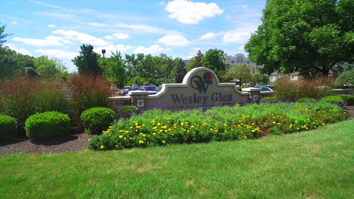 Sign for Wesley Glen surrounded by flowers and greenery