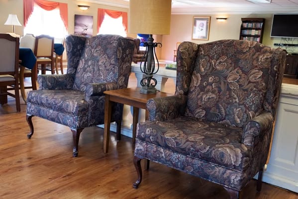 Two floral-patterned armchairs beside a small table in a common area