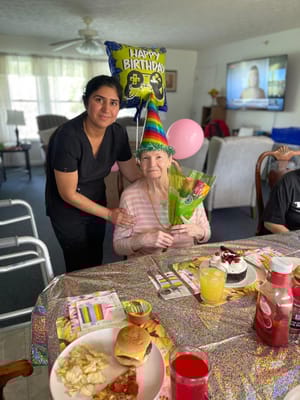 Resident celebrating a birthday with staff and decorations