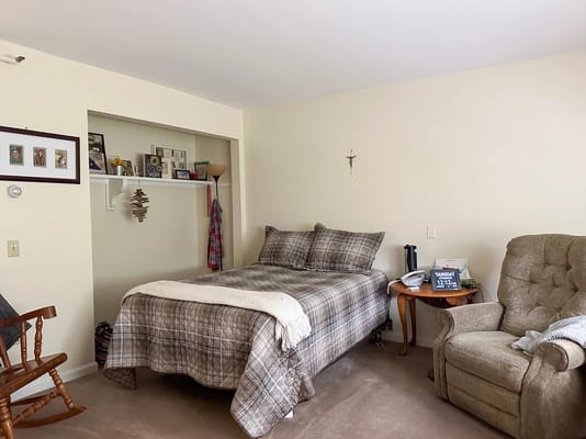 Cozy resident room featuring a bed, chair, and personal items