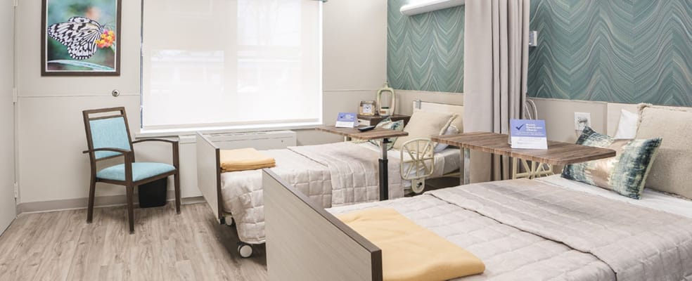 Bright shared room with two beds and a chair