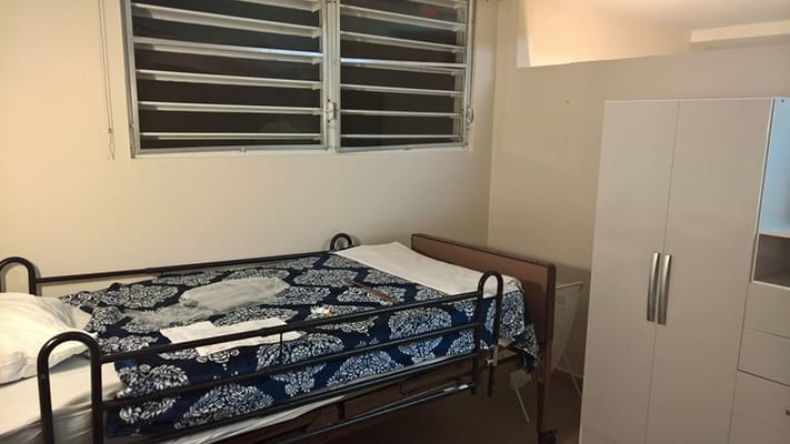 A bedroom with a hospital bed and wardrobe in Senderos Senior Living.
