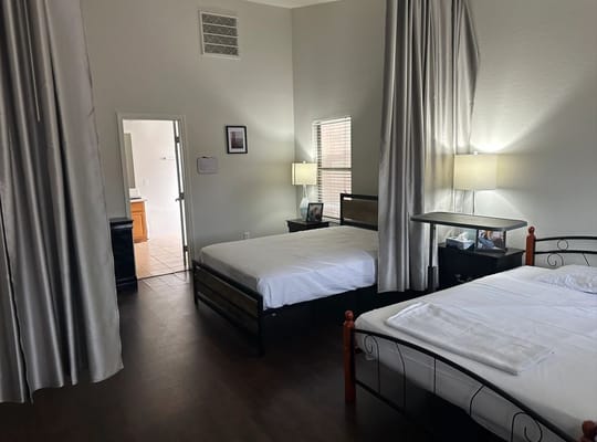 Bedroom with two beds and a bathroom door in the background