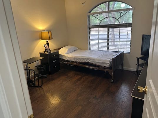 Cozy bedroom in assisted living facility with bed, lamp, and window