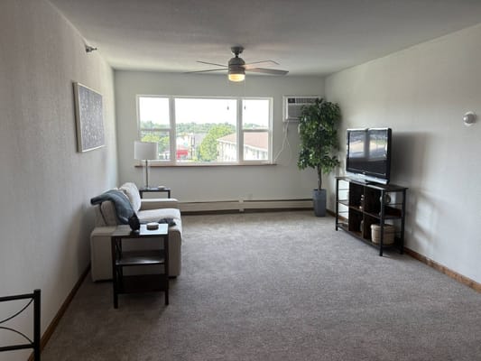 Spacious living room with a couch, TV, and window view