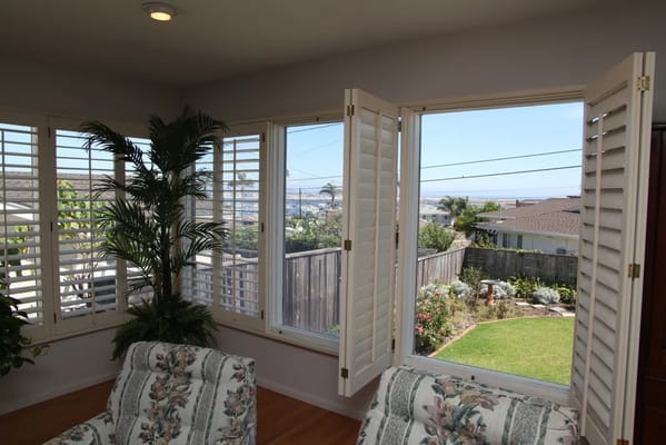 View from an interior space with shutters and greenery