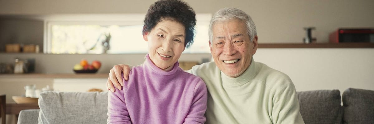 Two smiling residents sitting together on a sofa