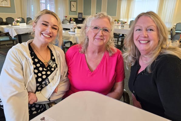 Three women smiling together in a communal area