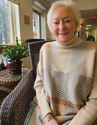 A smiling elderly woman sitting in the common area