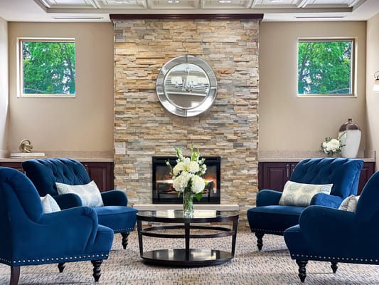 Cozy common area with blue chairs and a stone fireplace