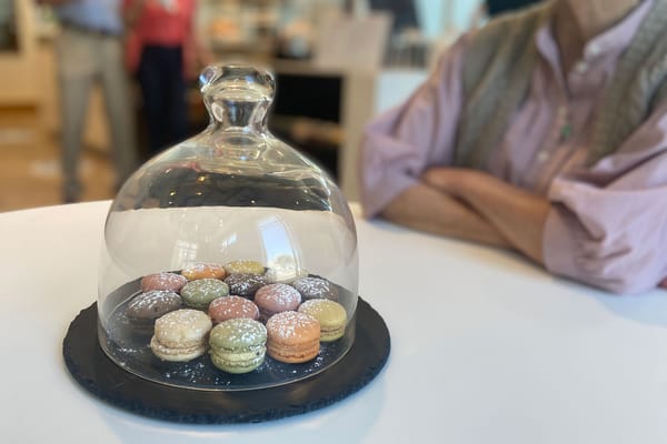 Colorful macarons presented under a glass dome in a dining area