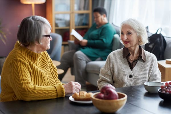 Two residents enjoying conversation over food in a common area
