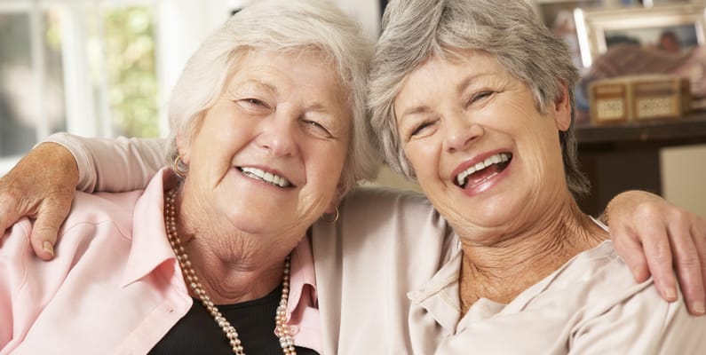 Two senior women smiling and embracing each other