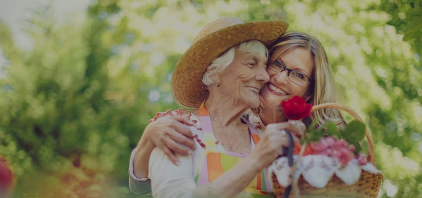 A resident and staff member smiling together in a garden