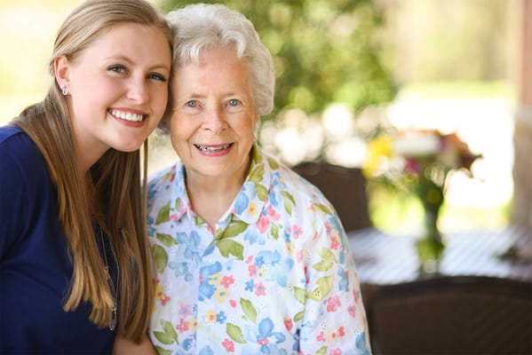 A caregiver smiling with a resident outdoors
