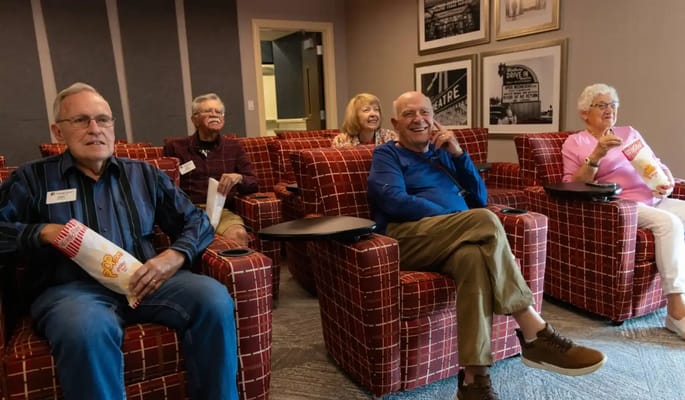 Residents enjoying a movie in a comfortable lounge area