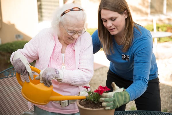 Resident and staff member gardening together outdoors