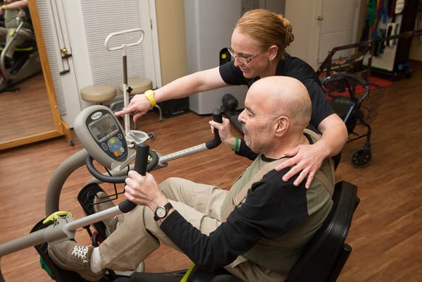 Staff assisting a resident with an exercise bike