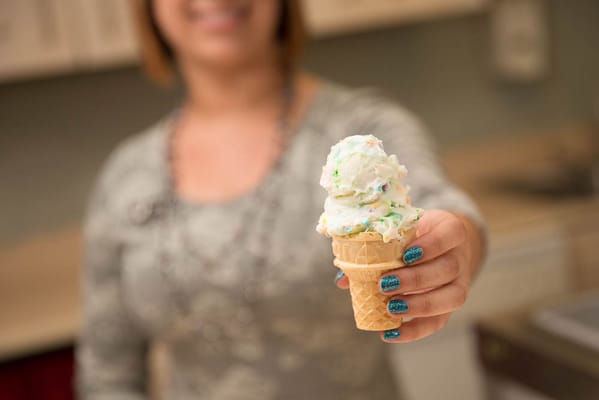 A staff member serving ice cream in a kitchen