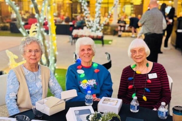 Three residents celebrating with festive lights on the patio