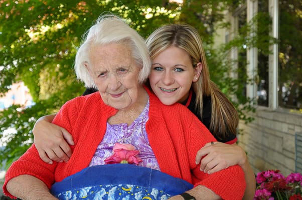 A resident and staff member smiling outside together