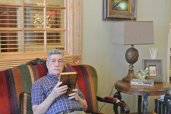 Resident reading a book in a cozy lounge area