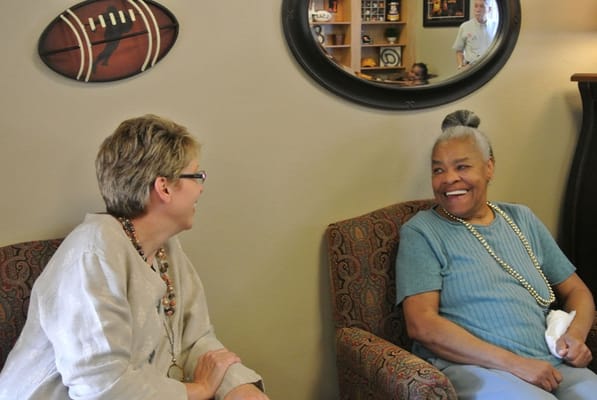 Staff member engaging with a smiling resident in a common area