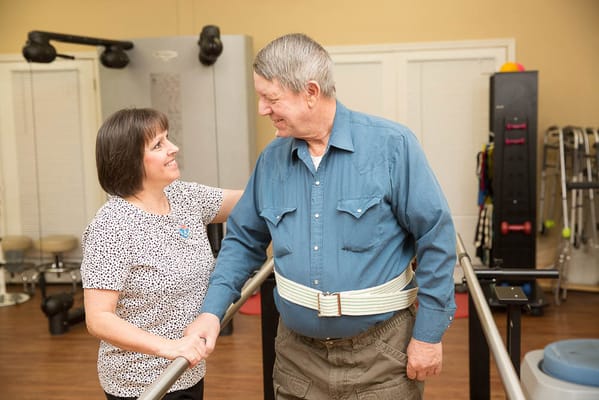 Therapist assisting a resident in a gym setting