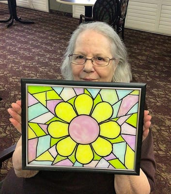 Resident showcasing a handmade stained glass flower