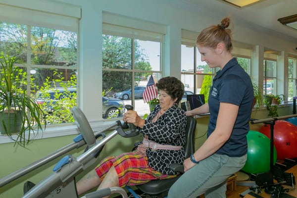 Resident using an exercise machine with staff assistance