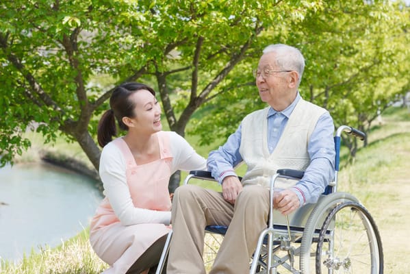 A caregiver interacting with a resident outdoors by a pond
