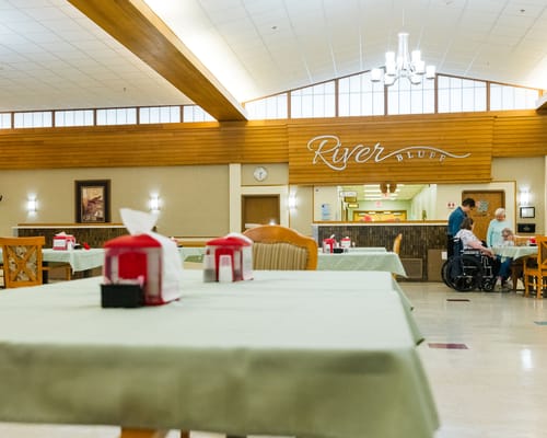 Interior view of the dining area with tables and residents interacting.