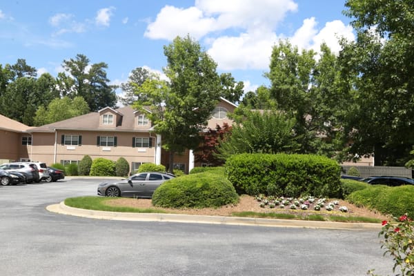 A view of the exterior of Summerset Assisted Living with landscaped gardens and parked cars.