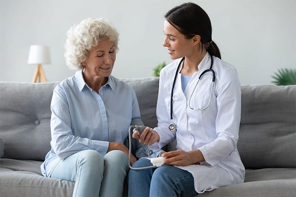 A caregiver taking a senior's blood pressure in a cozy setting