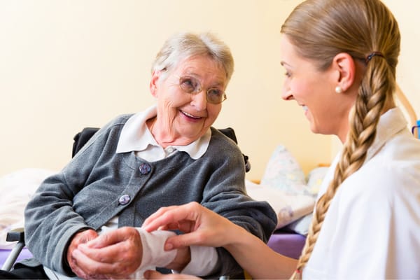 Caregiver assisting a smiling resident in a room