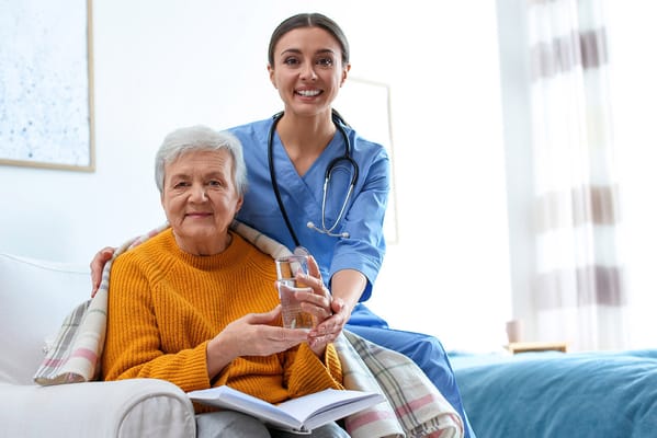 A caregiver providing water to a smiling senior resident
